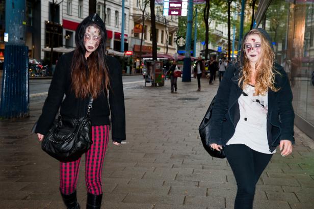Zwei als Zombies geschminkte Frauen gehen eine Straße entlang.