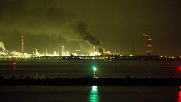 Eine nächtliche Ansicht einer beleuchteten Industrieanlage am Wasser.