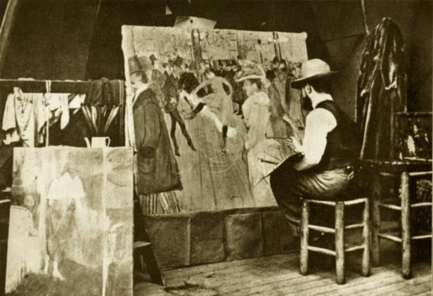 Ein Maler sitzt vor einer großen Leinwand in seinem Atelier.