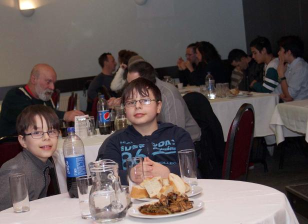 Zwei Jungen sitzen an einem Tisch mit Speisen und Getränken in einem Restaurant.
