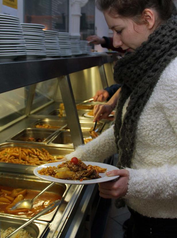 Eine Frau bedient sich an einem Buffet mit verschiedenen Speisen.