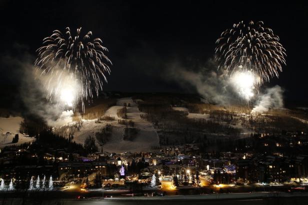Feuerwerk erhellt den Nachthimmel über einer verschneiten Stadt.
