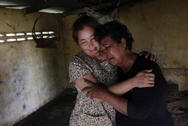 Zwei Frauen umarmen sich in einem einfachen Raum, eine weint.