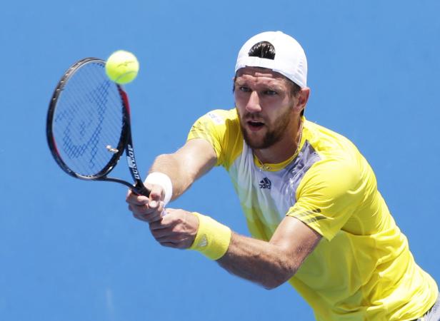 Ein Tennisspieler schlägt einen gelben Ball mit seinem Schläger.