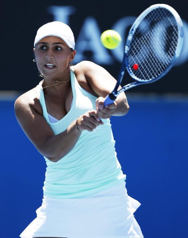 Eine Tennisspielerin schlägt einen Ball mit ihrem Schläger.