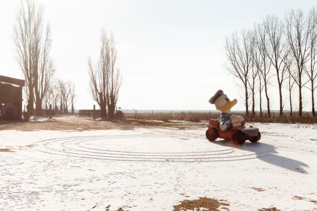 Eine Donald-Duck-Figur sitzt auf einem Spielzeugauto im Schnee.