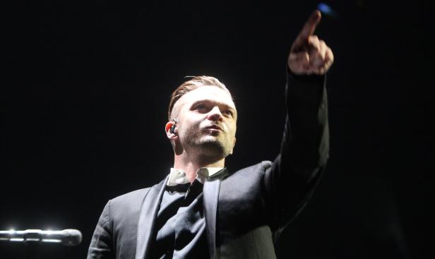 Justin Timberlake zeigt während eines Konzerts mit dem Finger nach oben.