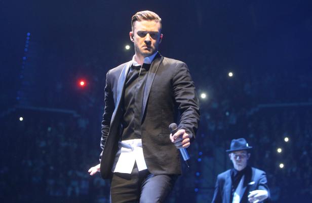 Justin Timberlake tritt in einem schwarzen Anzug auf einer Bühne auf.