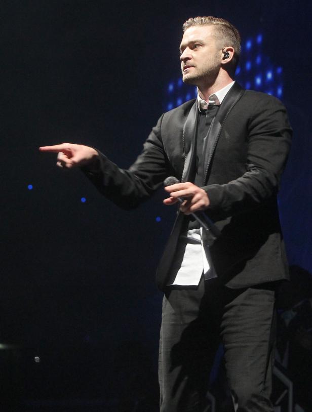 Justin Timberlake steht auf einer Bühne und zeigt mit dem Finger.