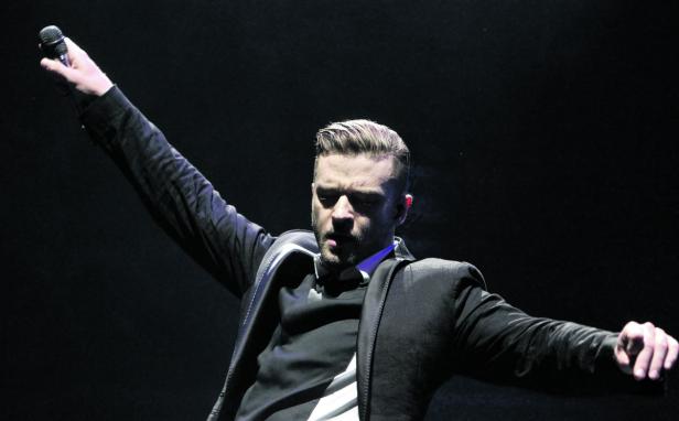 Justin Timberlake steht mit erhobenen Armen auf einer Bühne.