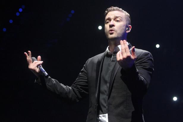 Justin Timberlake tritt auf einer Bühne mit einem Mikrofon in der Hand auf.
