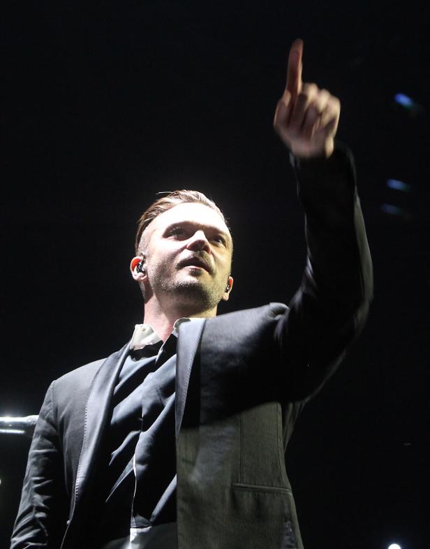 Justin Timberlake zeigt mit dem Finger nach oben.