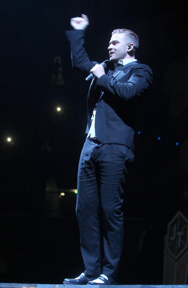 Justin Timberlake tritt in einem schwarzen Anzug auf einer Bühne auf.