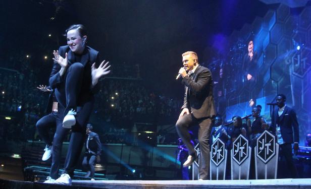 Justin Timberlake tritt mit Tänzern und Backgroundsängern auf einer Bühne auf.