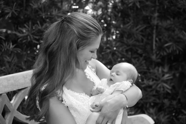 Eine lächelnde Mutter hält ihr schlafendes Baby im Arm.