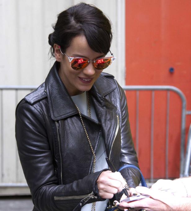 Lily Allen in Lederjacke signiert ein Autogramm.