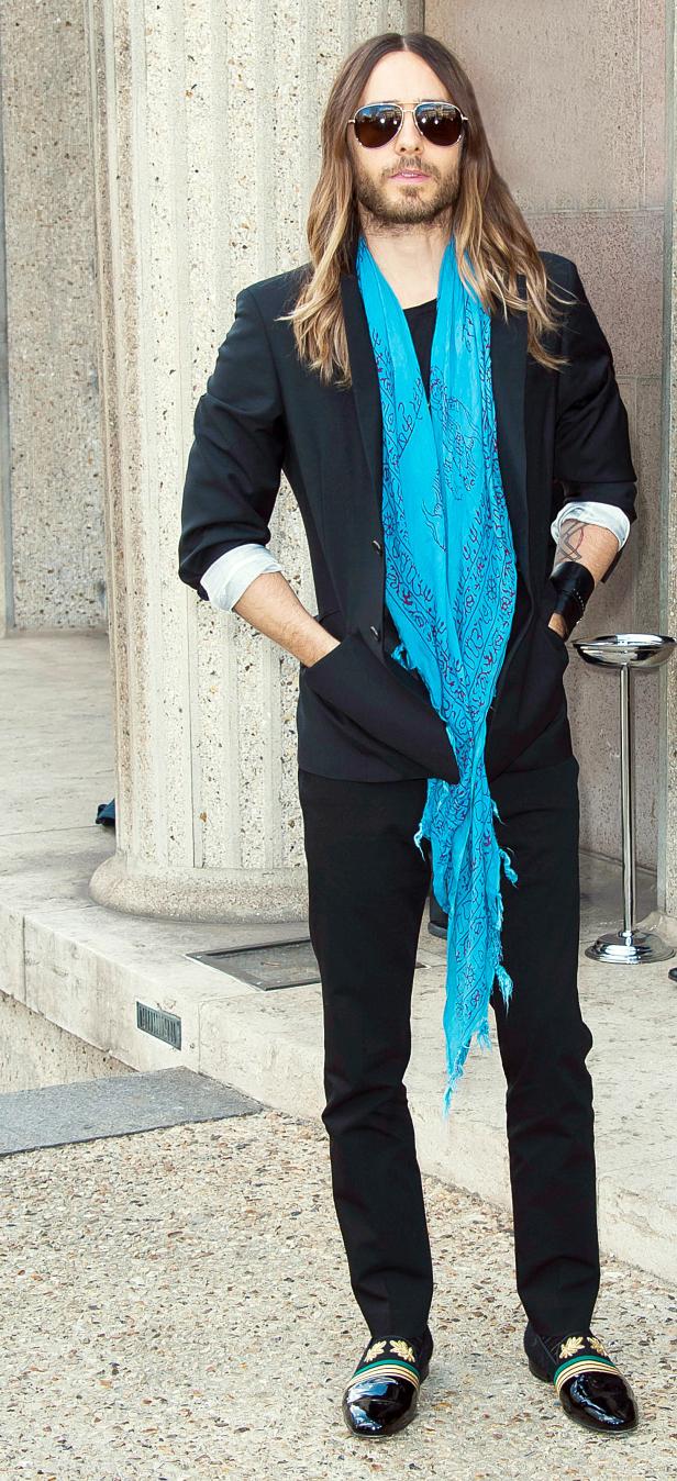 Jared Leto posiert mit Sonnenbrille und blauem Schal vor einem Gebäude.