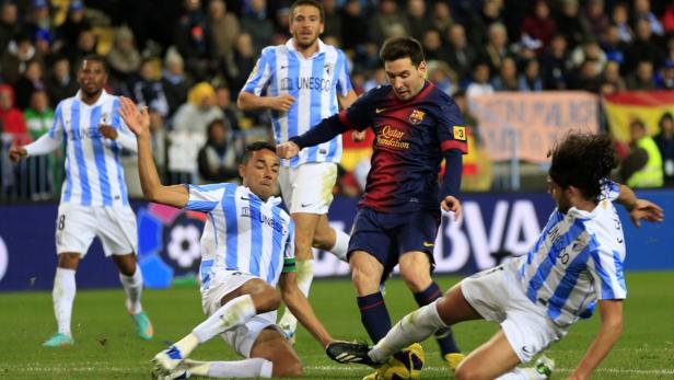 Lionel Messi im Zweikampf mit mehreren Spielern von Málaga während eines Fußballspiels.