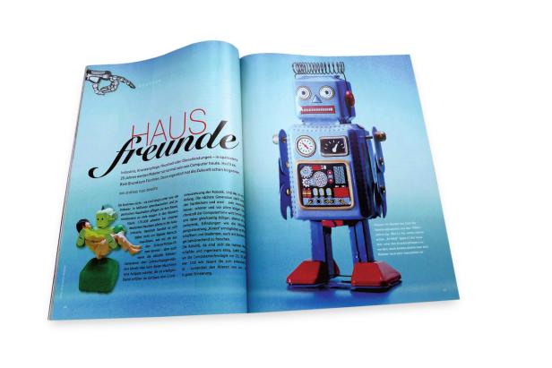 … Ein blauer Blechroboter steht auf einer Zeitungsseite über Robotik.