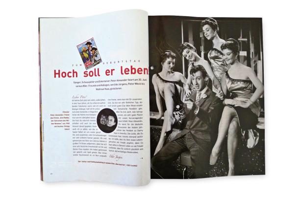 … Peter Alexander, umgeben von drei Frauen, hält eine Flasche in der Hand.
