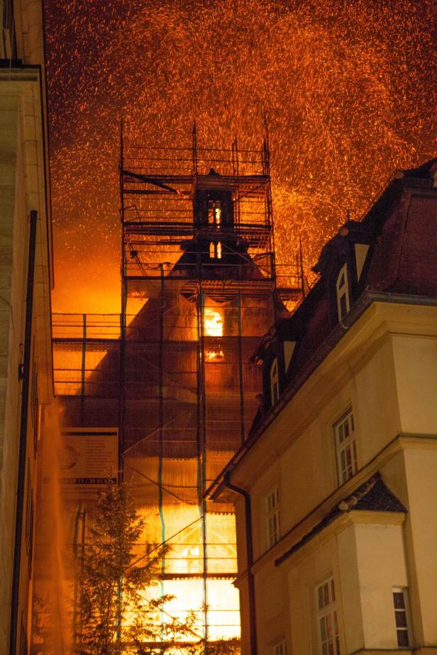 Ein Gebäude steht in Flammen, umgeben von einem Gerüst.