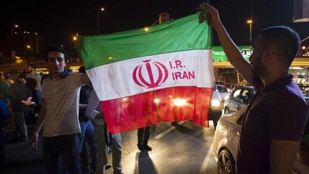 Menschen halten bei Nacht eine iranische Flagge hoch.