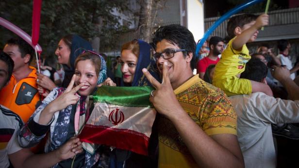 Menschen feiern mit der iranischen Flagge und Luftballons.