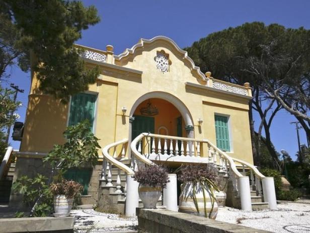 Ein gelbes Haus mit grünen Fensterläden und einer geschwungenen Treppe.