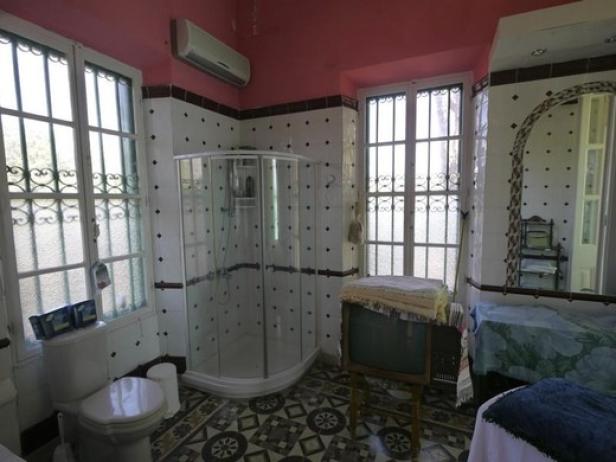Ein Badezimmer mit Dusche, Toilette und einem alten Fernseher mit Handtüchern darauf.