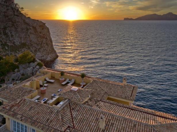 Blick auf eine Dachterrasse mit Liegestühlen bei Sonnenuntergang am Meer.