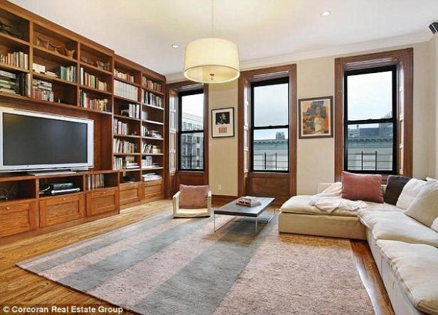 Ein Wohnzimmer mit Bücherregal, Fernseher, Sofa und großen Fenstern.