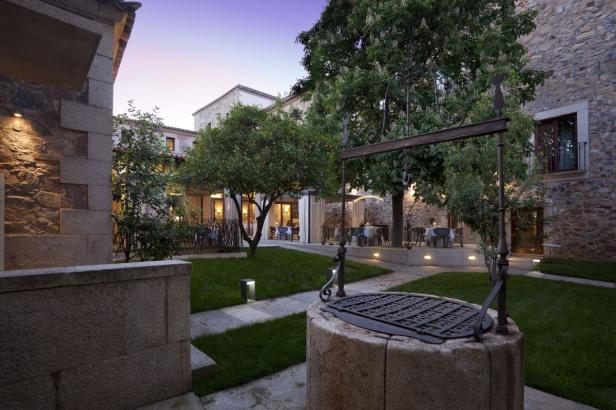 Ein Innenhof mit einem alten Brunnen und Tischen für ein Abendessen im Freien.