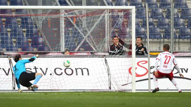 Ein Fußballtorwart versucht, einen Ball abzuwehren, während ein Spieler mit der Nummer 27 daneben steht.