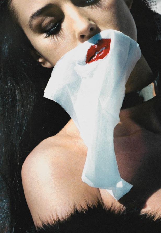 Eine Frau mit rotem Lippenstift wischt sich den Mund mit einem Tuch ab.