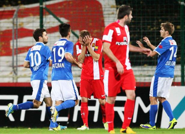 Fußballspieler in roten und blauen Trikots auf dem Spielfeld.