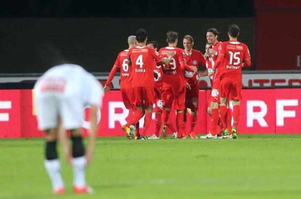 Fußballspieler in roten Trikots feiern gemeinsam auf dem Spielfeld.