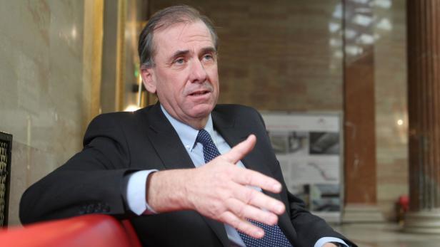 Ein Mann im Anzug gestikuliert während eines Gesprächs.