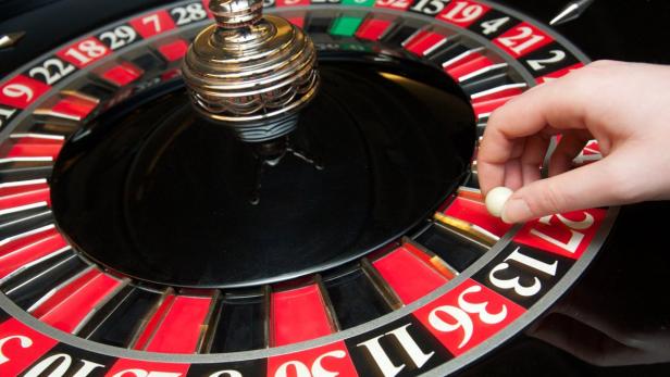 Eine Hand setzt eine Kugel in ein Roulette-Rad.