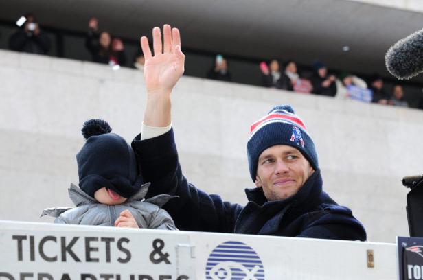 Tom Brady mit seinem Kind bei einer Parade.