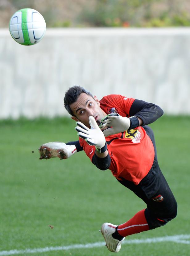 Ein Torwart hechtet nach einem Fußball.