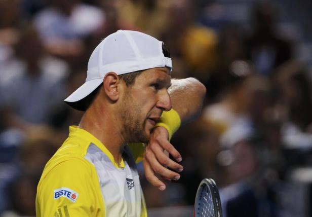 Ein Tennisspieler wischt sich den Schweiß von der Stirn.