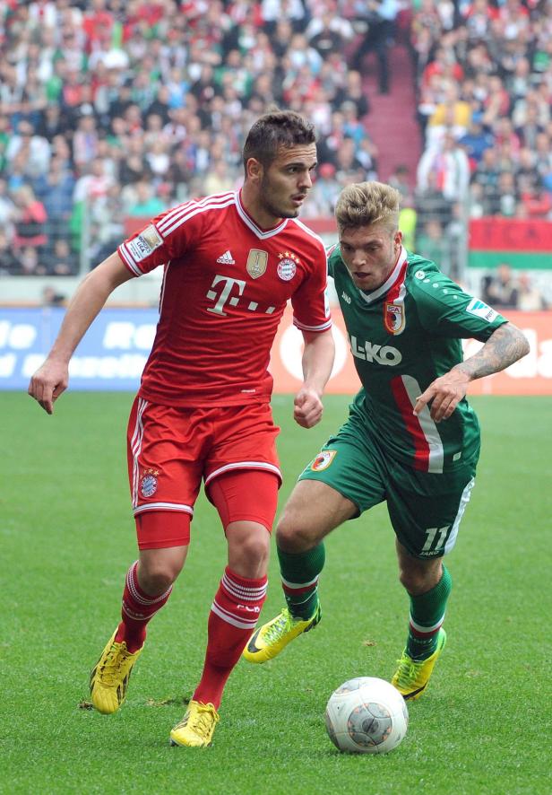 Zwei Fußballspieler kämpfen um den Ball auf dem Spielfeld.