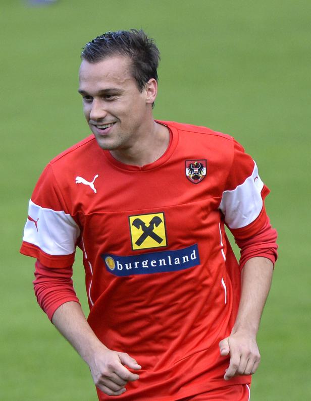 Ein lächelnder Fußballspieler im roten Trikot des österreichischen Nationalteams.