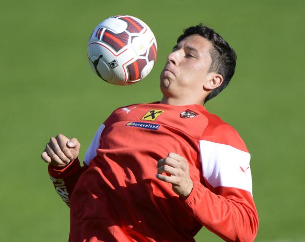 Ein Fußballspieler köpft einen Ball vor einem grünen Hintergrund.