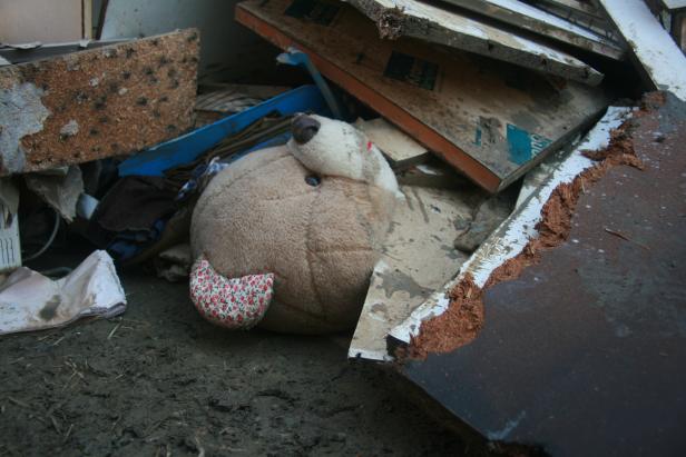 Ein Teddybär liegt inmitten von Trümmern und Schmutz.