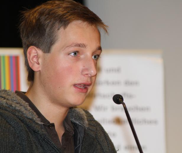 Ein junger Mann spricht in ein Mikrofon.