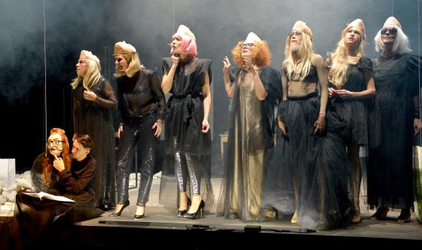 Eine Theaterszene mit mehreren Darstellern in ungewöhnlichen Kostümen und Masken.