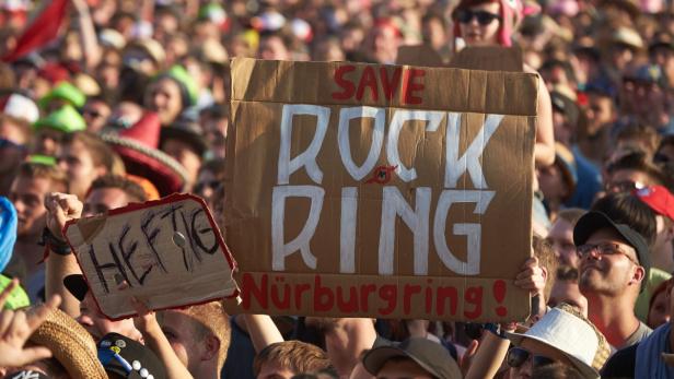 Eine Menschenmenge hält Schilder mit der Aufschrift „Save Rock Ring Nürburgring!“.