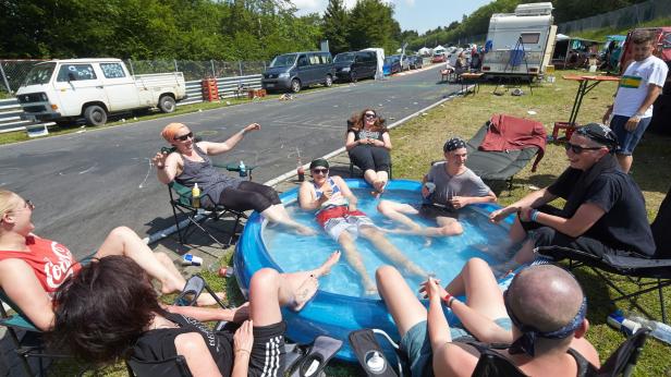 Eine Gruppe von Menschen entspannt sich in einem Pool am Rande einer Rennstrecke.