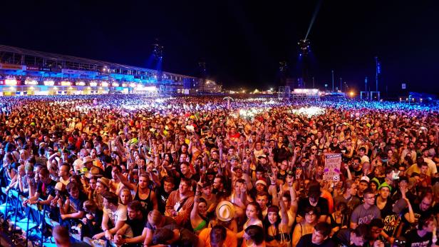 Eine große Menschenmenge jubelt bei einem Konzert im Freien.